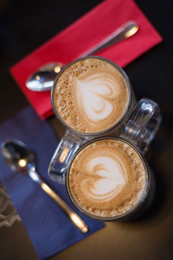 A picture of two drinks with hearts in the foam for this post on why to never stop dating your husband.