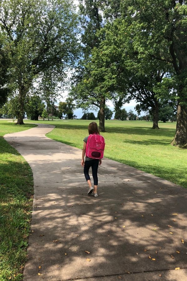 A picture of a child with a backpack walking down the sidewalk for this post about letting go on the first day of kindergarten.