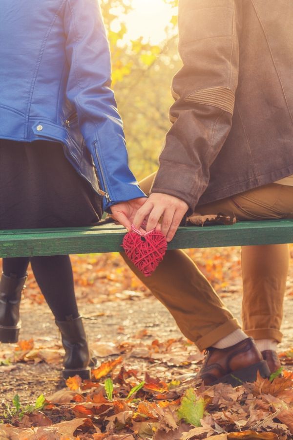 A couple holding hands on a park bench for this post on how to love your husband unconditionally.