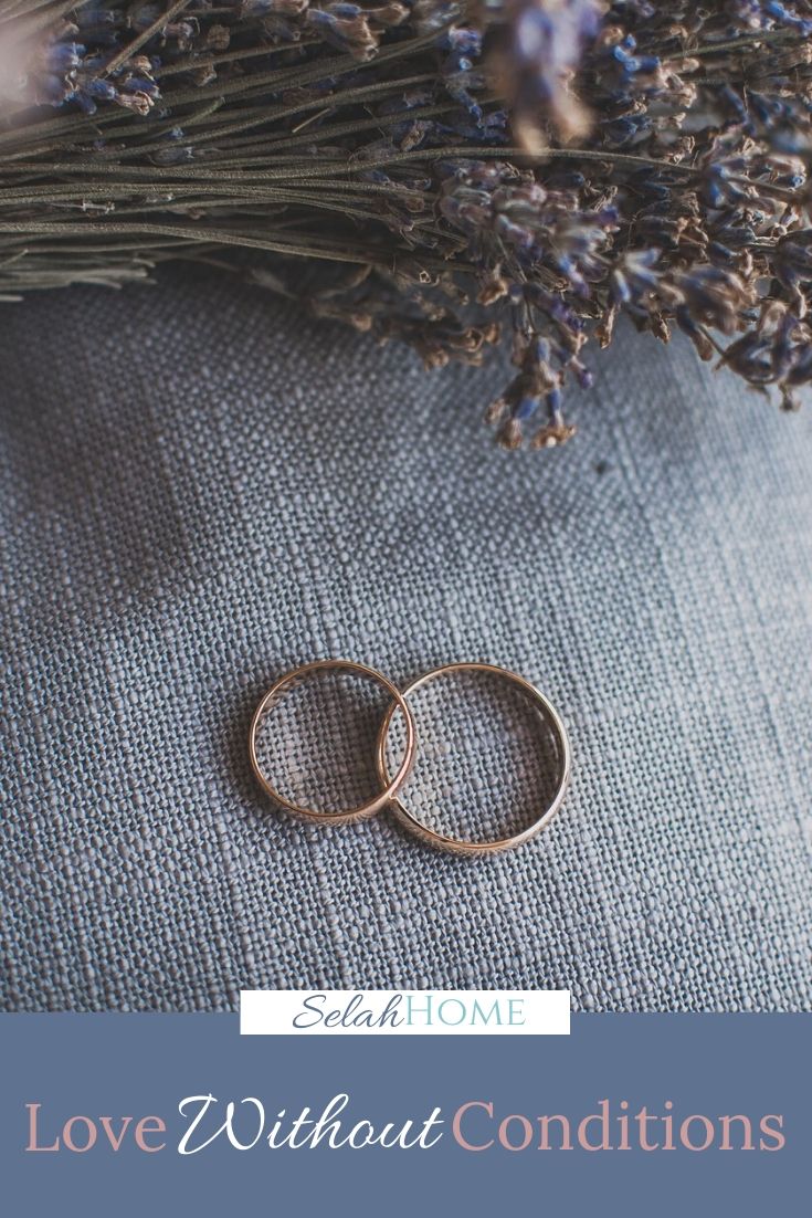 A Pinterest pin with a picture of two wedding rings beside blue flowers. Designed for this post about the importance of a love without conditions in marriage.