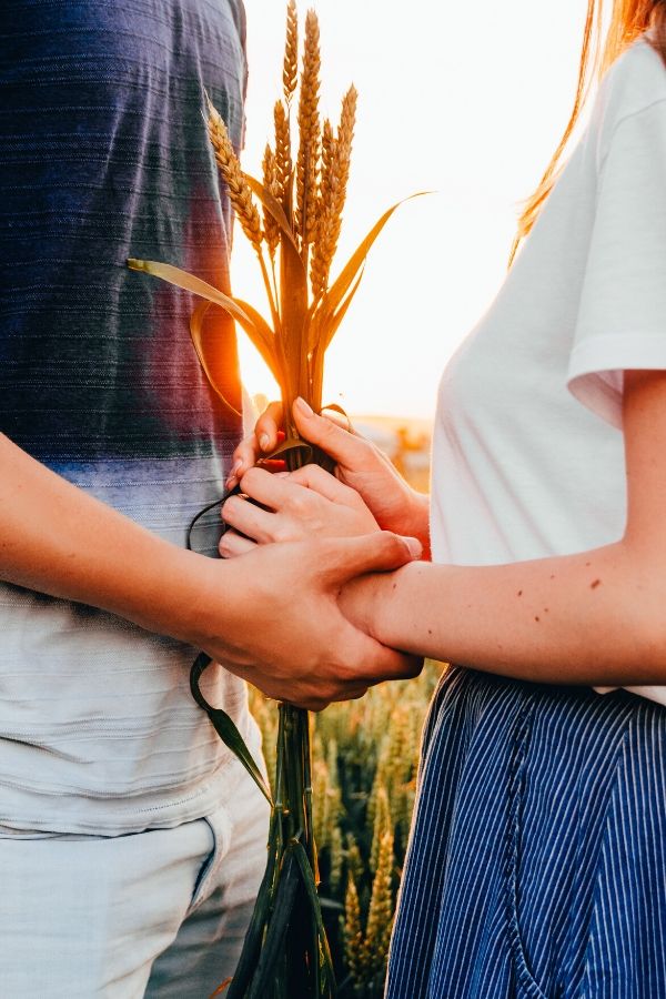 A picture of a couple holding hands in a wheat field for this post about personality differences in marriage.