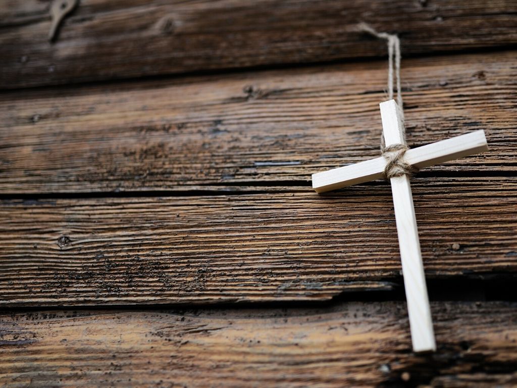 A picture of a white cross on a wooden background for this post about overcoming fear with faith.