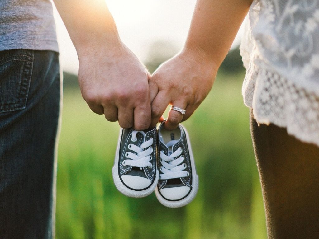A picture of a couple holding baby shoes for this post of parenting resources.