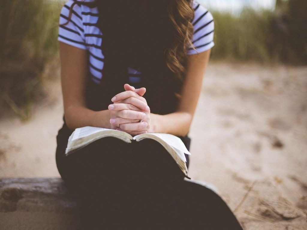 A picture of a woman praying with an open Bible for this post on effective ways to pray for your husband.