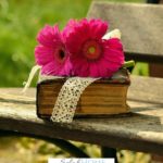 A Pinterest pin with a picture of an old Bible and pink flowers sitting on a bench. Designed for this post of scriptures for moms.