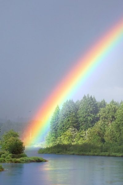 A picture of a rainbow stretching across a lake for this post about the miracles and wonders of God.