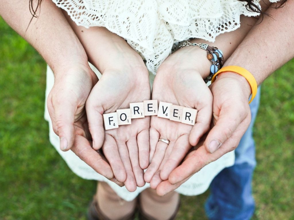 A picture of a couple holding the word "forever" for this post about increasing joy in marriage.