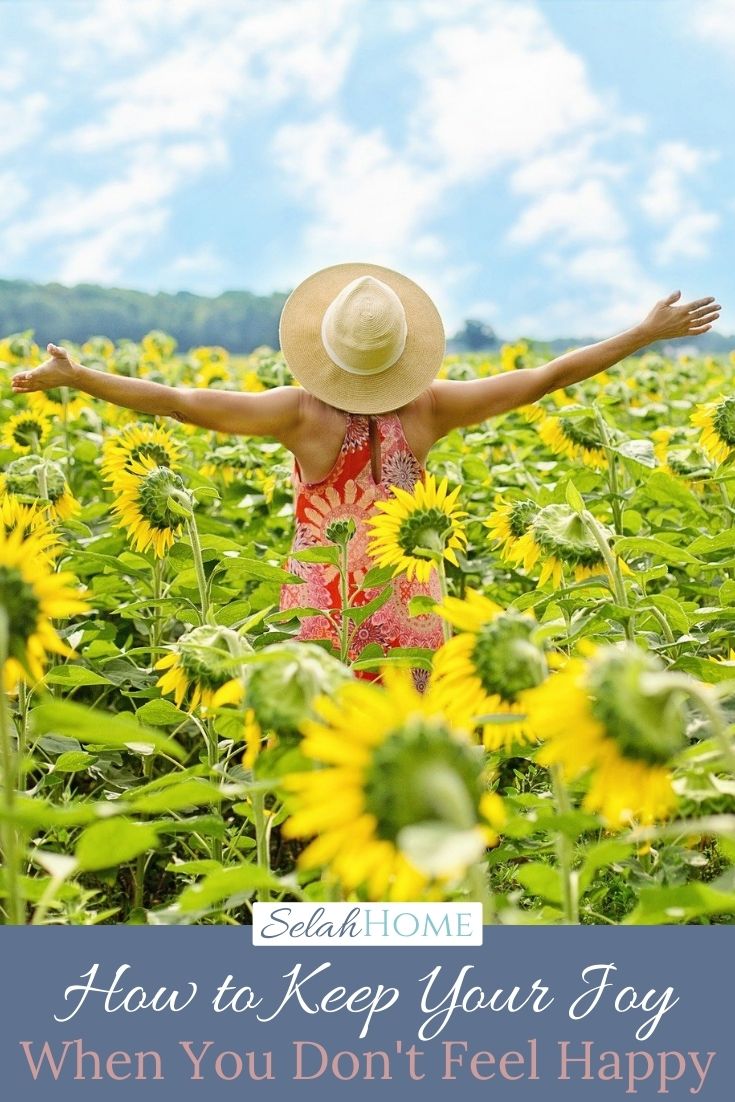 A Pinterest pin with a picture of a woman in a field of sunflowers. Designed for this post about how to keep your joy.
