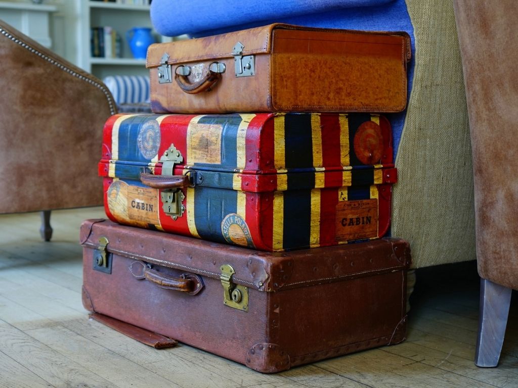 A picture of a pile of suitcases for this post that includes a family road trip packing list.