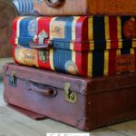 A Pinterest pin with a picture of a pile of suitcases. Designed for this post that includes a family road trip packing list.