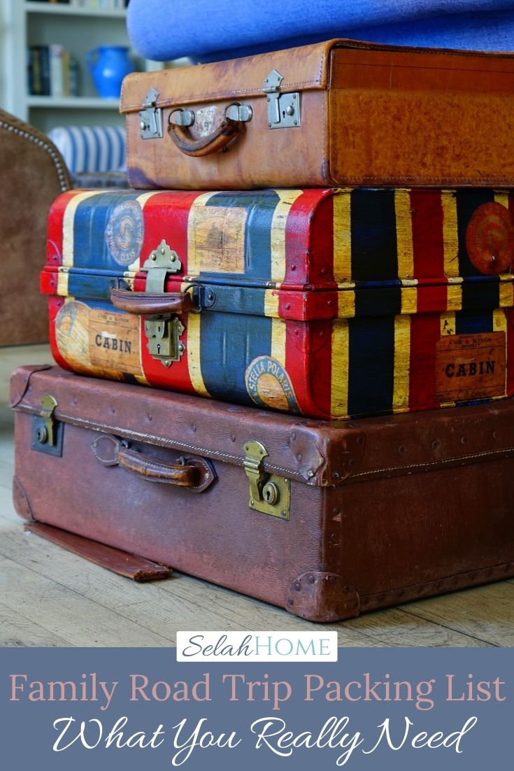 A Pinterest pin with a picture of a pile of suitcases. Designed for this post that includes a family road trip packing list.