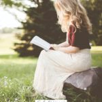 A Pinterest pin with a picture of a woman reading in a sunlit field. Designed for this post about how to be a more patient mom.
