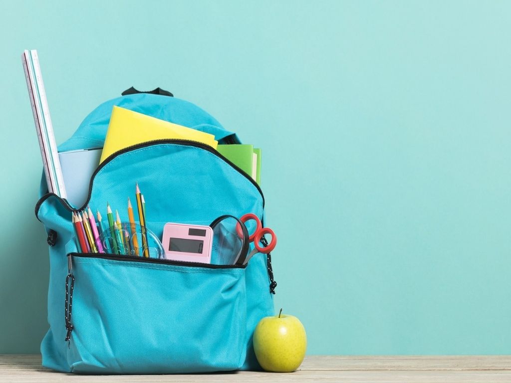 A picture of a backpack stuffed with school supplies for this post about a practical school morning routine list for families.