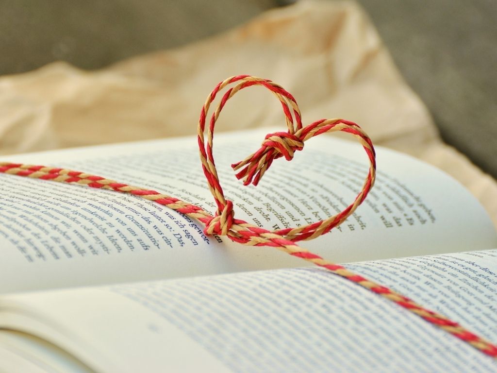 A picture of an open book tied with a string in the shape of a heart for this post about raising a reader.