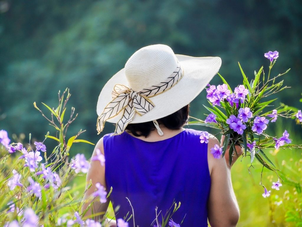 A picture of a woman collecting flowers in an open field for this post about grief and hope after miscarriage.