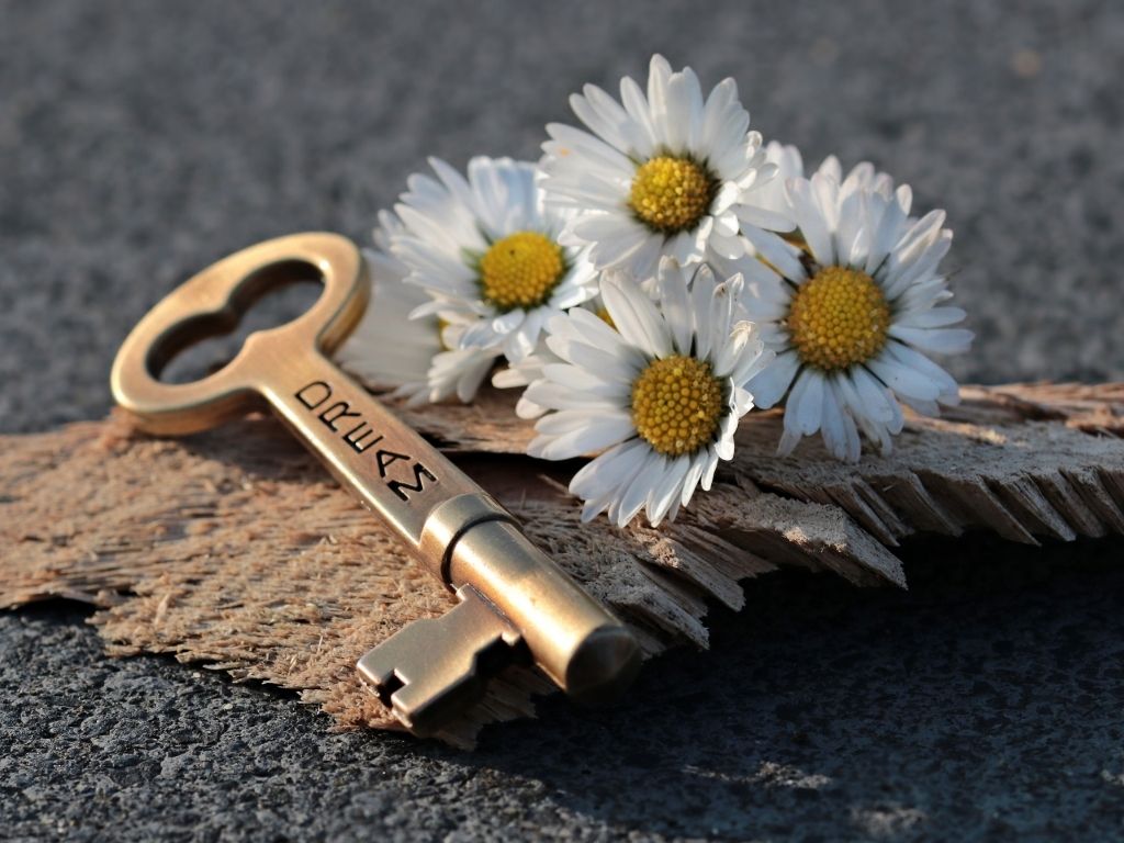A picture of white flowers and a key with the word dream engraved on it for this post about marriage vision.