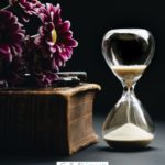 A Pinterest pin with a picture of an hourglass, flowers, and book. Designed for this post about what to do while waiting on God.
