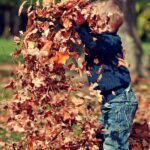 A picture of a little boy playing in the leaves for this post about embracing motherhood.