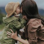 A picture of a little girl kissing her mom's cheek for this post about being a present parent.