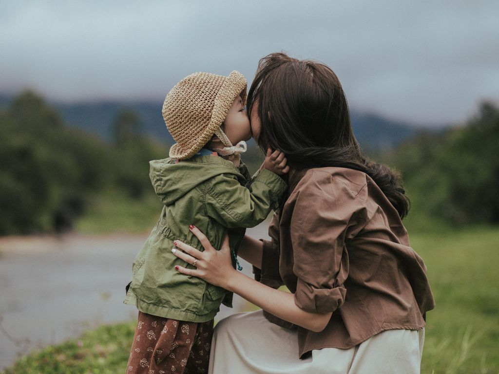 A picture of a little girl kissing her mom's cheek for this post about being a present parent.