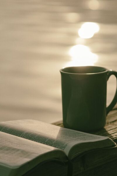 A picture of a Bible and coffee cup sitting by the water for this post of bible verses for anxiety and fear.