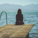 A picture of a woman sitting on a dock for this post asking what does God say about emotions?