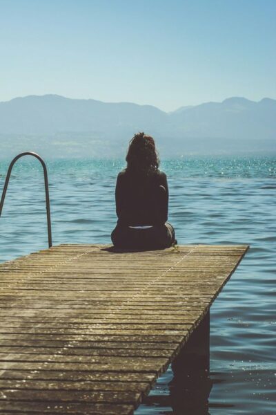 A picture of a woman sitting on a dock for this post asking what does God say about emotions?