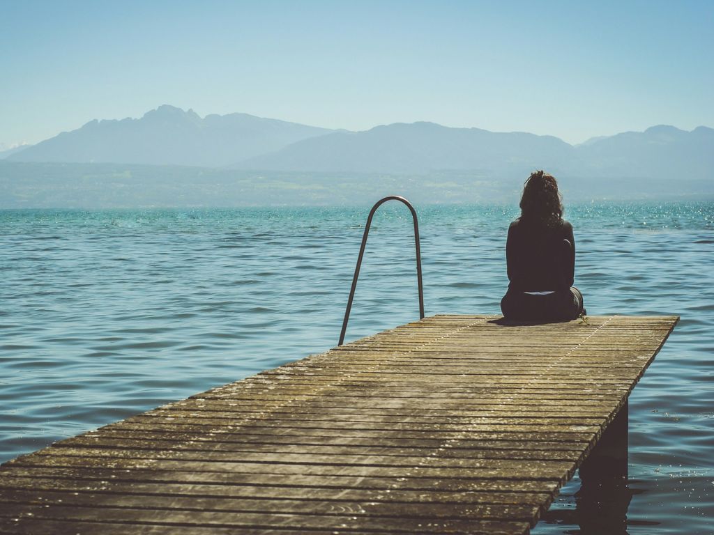 A picture of a woman sitting on a dock for this post asking what does God say about emotions?