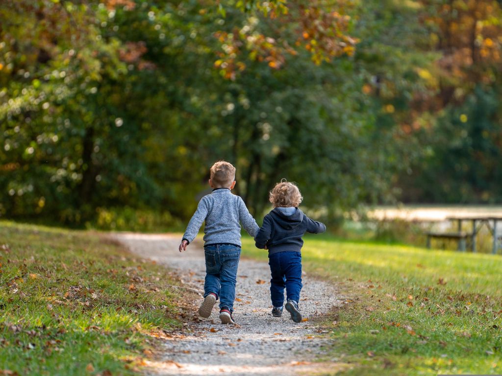 A picture of two kids running outside for this post of 10 ways to get kids to unplug and play.