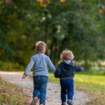 A picture of two kids running outside for this post of 10 ways to get kids to unplug and play.