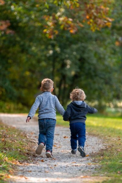 A picture of two kids running outside for this post of 10 ways to get kids to unplug and play.